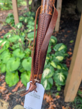Brown leather grip on walking stick with braided design on a blurred natural background