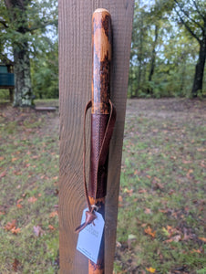 Hickory Walking Stick with leather grip on a wooden post outdoors