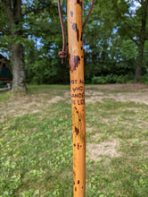 Outdoor picture of a walking stick with the carved quote, " Not all who wander are lost." 