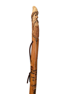 Walking stick with a carving of Gandalf at the top and the quote, "Home is now behind you. The world is ahead. -Gandalf"
