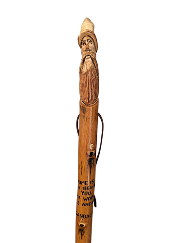 Walking stick with a carving of Gandalf at the top and the quote, 